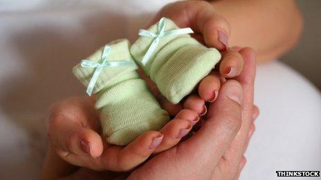 Parents holding green baby socks