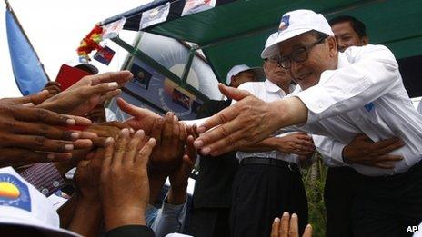 Sam Rainsy, president of the Cambodia National Rescue Party, shakes hands with his party supporters during an election campaign rally at Kampong Speu province, west of Phnom Penh, Cambodia, 20 July 2013