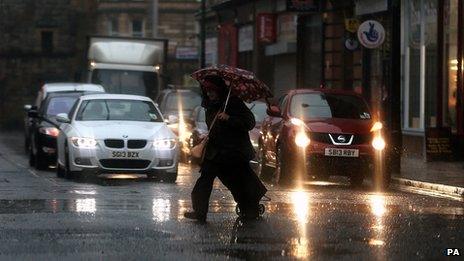 A woman under an umbrella in heavy rain in Glasgow