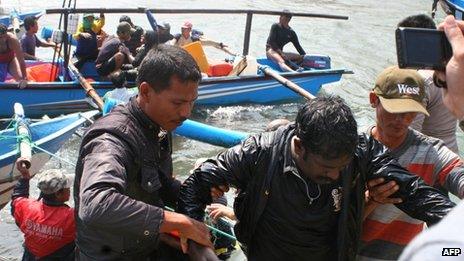 Rescuers assist a survivor on arrival at the wharf of Cidaun, West Java on 24 July 2013 after an Australia-bound boat carrying asylum-seekers sank off the Indonesian coast