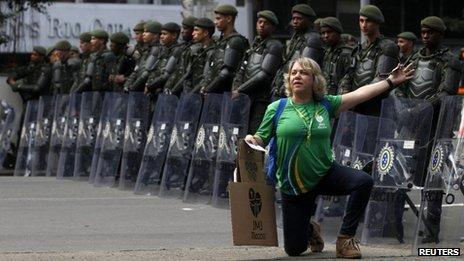 Pilgrim poses in front of riot police in Rio de Janeiro