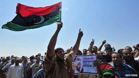 Men hold up a picture of prominent Libyan political activist Abdelsalam al-Mismari during his funeral in Benghazi on 27 July, 2013