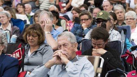 Mourners watch a memorial service on screen outside Saint Agnes church in Lac Megantic on 27 July, 2013, three weeks after a runaway oil train derailed and exploded in the town, killing 47 people