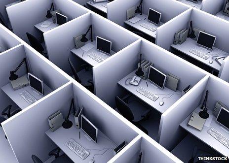 Rows of small cubicles with desks and computers