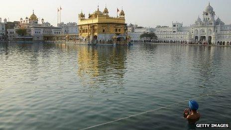 A Sikh man takes a dip in the water beside the Golden Temple