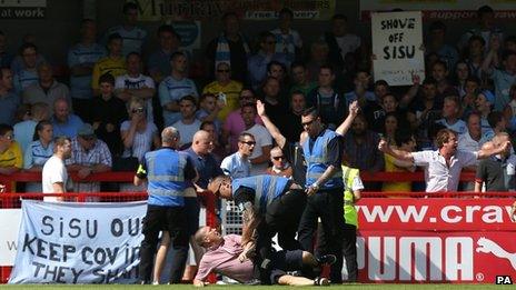 Stewards wrestling one of the protesting Coventry fans to the ground