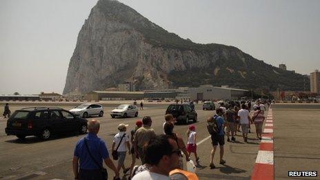 Pedestrians and drivers cross the tarmac of the Gibraltar International airport in front of the Rock of the British Colony of Gibraltar on 4 August