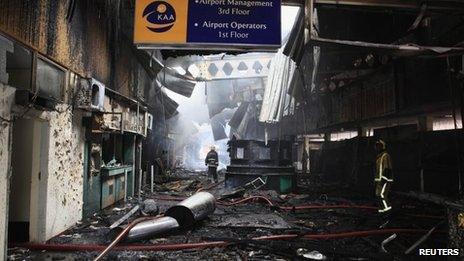 Firefighters walk amid debris from a fire at the Jomo Kenyatta International Airport in Kenya's capital Nairobi on Wednesday