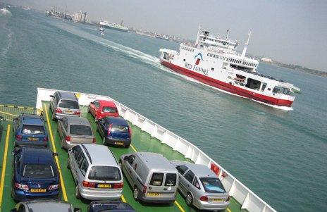 A photo of one ferry taken from another ferry, of which several cars are visible on the deck