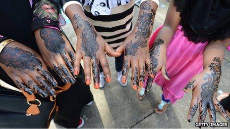 Young Muslim girls show their hands decorated with henna after attending prayers on Eid Al-Fitr at the Regent's Park Mosque in London on August 19, 2012