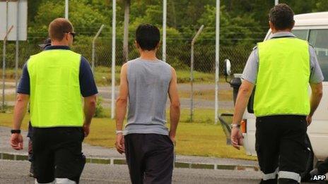 Australian Government Department of Immigration and Citizenship hand-out photo taken on 1 August 2013 shows officials (L and R) walking with one of the first group of 40 asylum-seekers arriving on Manus Island, Papua New Guinea since Australia's policy shift