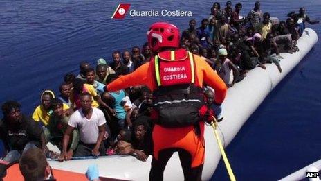 An Italian coast guard talks to African migrants aboard a boat off Lampedusa, 9 August