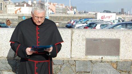 Canon Paul Mellor conducting a service on Holocaust day by the Guernsey Holocaust memorial plaque