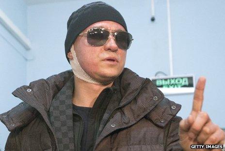 Sergei Filin is shown with a bandage around his neck, wearing a hat and dark glasses