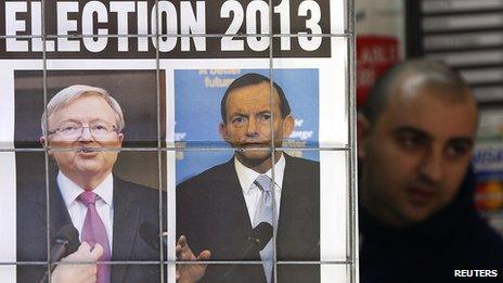 A man walks behind a newspaper ad picturing Australian Prime Minister Kevin Rudd (L) and opposition leader Tony Abbott in Sydney on 5 August 2013