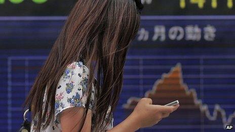 A woman walks while looking at her smartphone