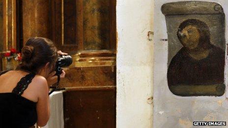 A tourist takes a photograph of Ecce Homo