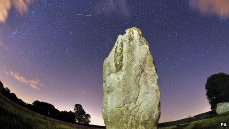 A meteor is seen during the Perseids meteor shower over the one of the stones of the Avebury"s Neolithic henge monument in Wiltshire