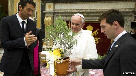 Pope Francis receives a gift from Argentina's soccer player Lionel Messi (R) and Italy's goalkeeper Gianluigi Buffon (L) during a private audience at the Vatican, 13 August, 2013.