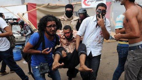 People carry an injured protester at Nahda Square in Cairo during clashes between supporters of Egypt's ousted president Mohamed Morsi and riot police on August 14, 2013