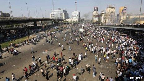 Smoke rises in the distance as supporters of ousted Egyptian President Mohammed Morsi are seen in Cairo 16 August, 2013.