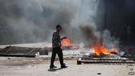 An Egyptian Muslim Brotherhood supporter walks near fires in Cairo's Ramses square on 16 August, 2013.