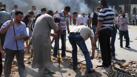 Egyptian Muslim Brotherhood supporters break up the pavement to collect rocks to throw towards police as clashes broke out in Cairo's Ramses square on 16 August, 2013