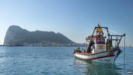 A Spanish fishing boat in the sea, with the Rock of Gibraltar in the background