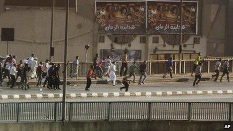 A man, centre, holding a gun takes his position while having gunfire with other civilians in Cairo, Egypt (16 August 2013)