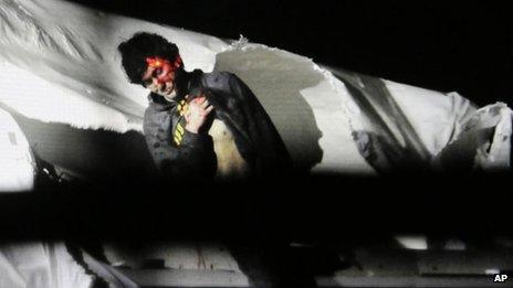 Massachusetts State Police photo, Dzhokhar Tsarnaev, bloody and dishevelled with the red dot of a sniper's rifle laser sight on his head, emerges from a boat at the time of his capture by law enforcement authorities in Watertown, Massachusetts 19 April 2013