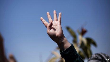 Supporter of Muslim Brotherhood gives a symbolic salute in Cairo, Egypt, on 18 August 2013