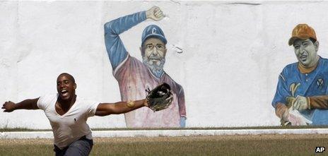 A prisoner plays baseball at the Combinado del Este prison, where a mural of Cuban leader Fidel Castro and Venezuela President Hugo Chavez cover a wall, in Havana, Cuba, Tuesday, 9 April, 2013