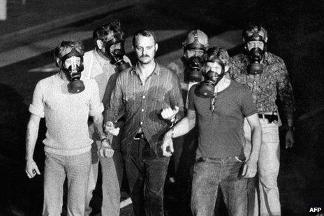 police officers wearing gas masks escorting Jan-Erik Olsson (C) in handcuffs after a hostage drama at the Kreditbanken bank