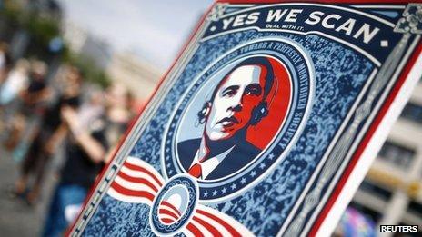 A protester holds a placard showing U.S. President Barack Obama with the phrase "Yes we scan"