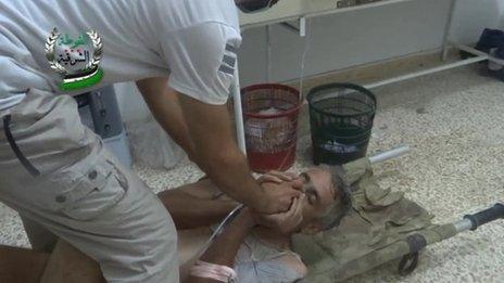 Alleged victim of chemical weapons attack covers his face as he is given an oxygen mask to help him breathe on 21 August 2013