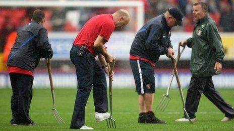 Groundstaff tend to the sodden playing surface at the The Valley