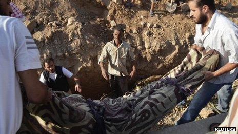 The body of a victim of a suspected chemical weapons attack is lowered into a grave in Hamoria, Damascus (21 August 2013)