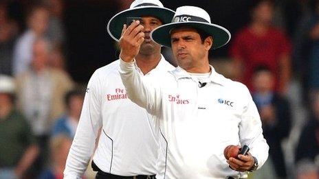 Umpires Aleem Dar and Kumar Dharmasena assess the light meter