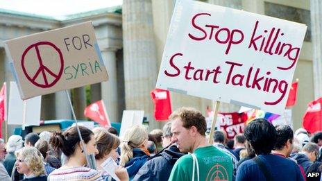 Protesters against arms exports and a military strike against Syria hold placards reading "for Syria" and "Stop killing, start talking" in front of the Brandenburg Gate in Berlin, Germany on 1 September 2013