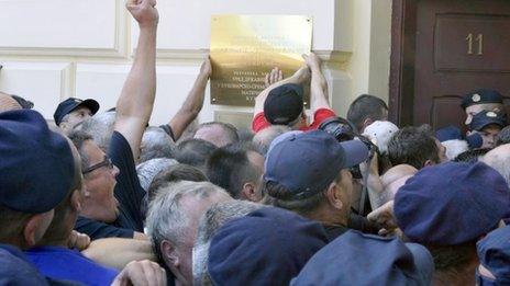 Protesters pull down a plaque from a local government building in Vukovar, eastern Croatia