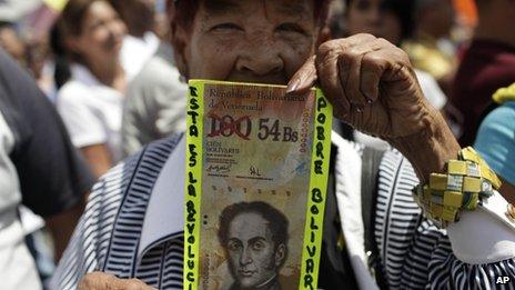 A man holds up a fake Bolivar bill at a protest march in February 2013