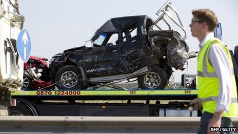 Recovery worker walks past wrecked cars