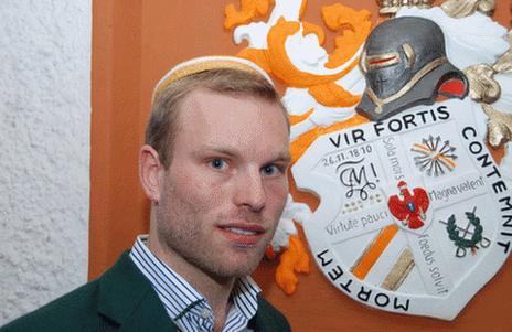 German student fencer Nils Hempel stands in front of the coat of arms of his fraternity in Berlin, the Corps Marchia