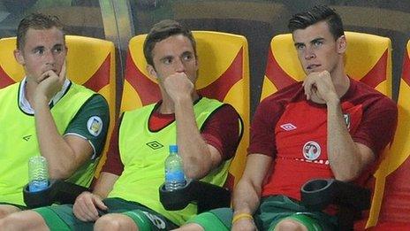 Gareth Bale (right) looks on from the Wales bench as they fall to defeat in Macedonia