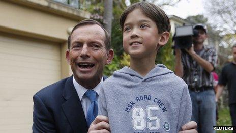 Tony Abbott with the son of a supporter as he leaves his house in Sydney on 8 September 2013