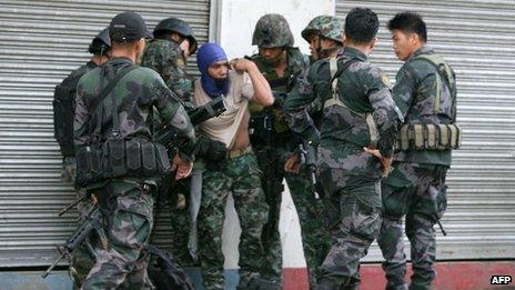 Combat police forces check on their comrade (centre) who was hit by sniper fire in downtown Zamboanga in the Philippines on 9 September 2013