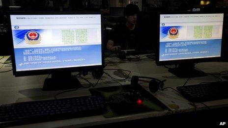 A computer user sits near displays with a message from the Chinese police on the proper use of the internet at an internet cafe in Beijing, China, Monday, 19 August 2013