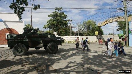 Residents walk past a government military vehicle as they evacuate near an area where members of Muslim rebels Moro National Liberation Front (MNLF) have occupied in Zamboanga city, southern Philippines, 9 September 2013