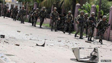 Security forces walks past debris scattered on a street after rebels from the Moro National Liberation Front (MNLF) clashed with government troops in Zamboanga city, southern Philippines, 9 September 2013