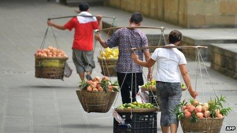 This picture taken on 8 August 2013 shows a vegetable vendors carrying their produce to sell in China's south-west metropolis of Chongqing